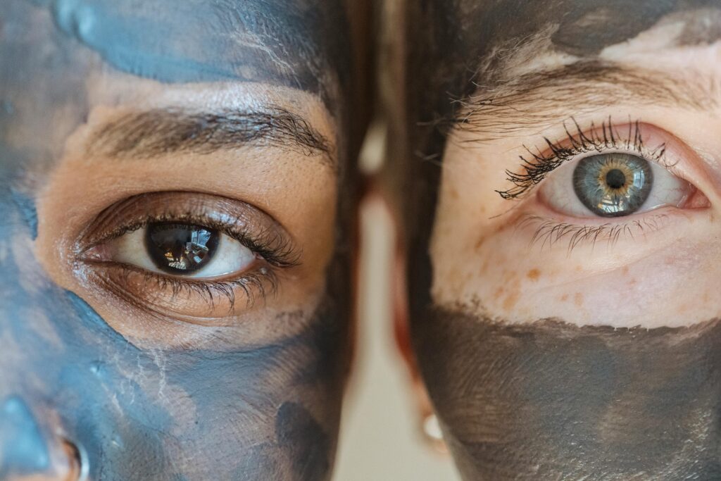 Closeup portrait of two women with facial masks, highlighting diversity and skincare routines.